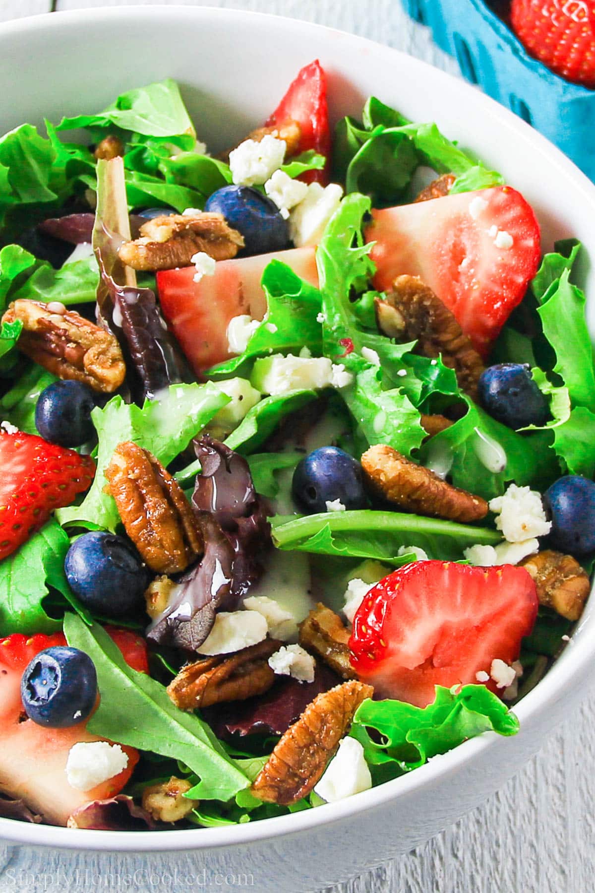 A fresh strawberry spinach salad with pecans. This summer salad recipe is bursting with flavor from the fresh berries, toasted pecans, & poppy seed dressing. #spinachsalad #simplesalad #summersalad #strawberrysalad #poppyseeddressing Close up of Strawberry Feta Spinach Salad