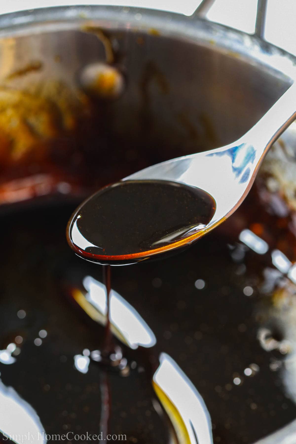 A spoonful of Balsamic Glaze dripping into a pot.