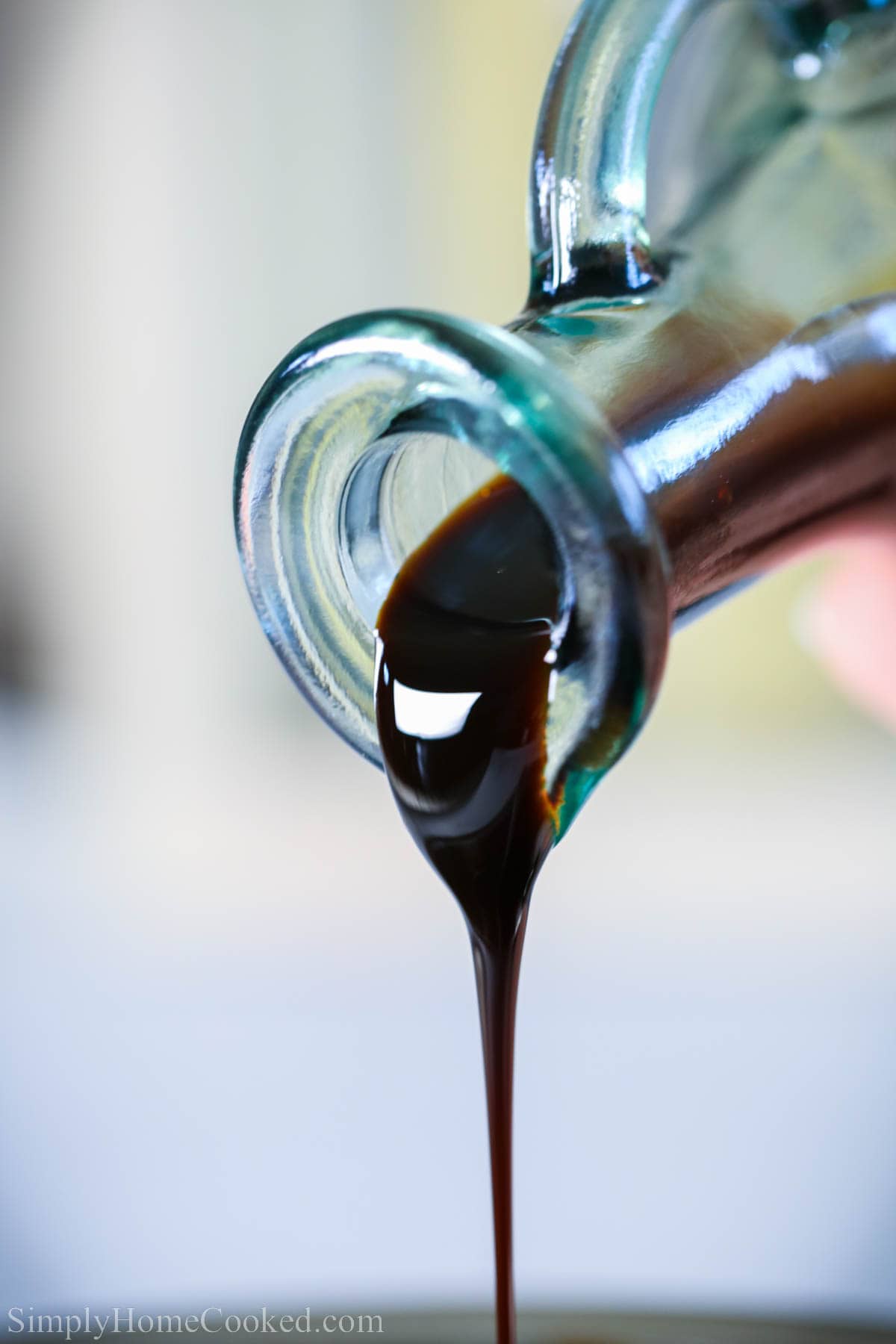 The best and easiest 2 ingredient balsamic glaze (reduction) that will become your favorite condiment for chicken, salads, steaks, and Caprese. #balsamicreduction #balsamicglaze #glaze #balsamicsauce #capesesauce #vinegarsauce A cruet pouring out Balsamic Glaze.