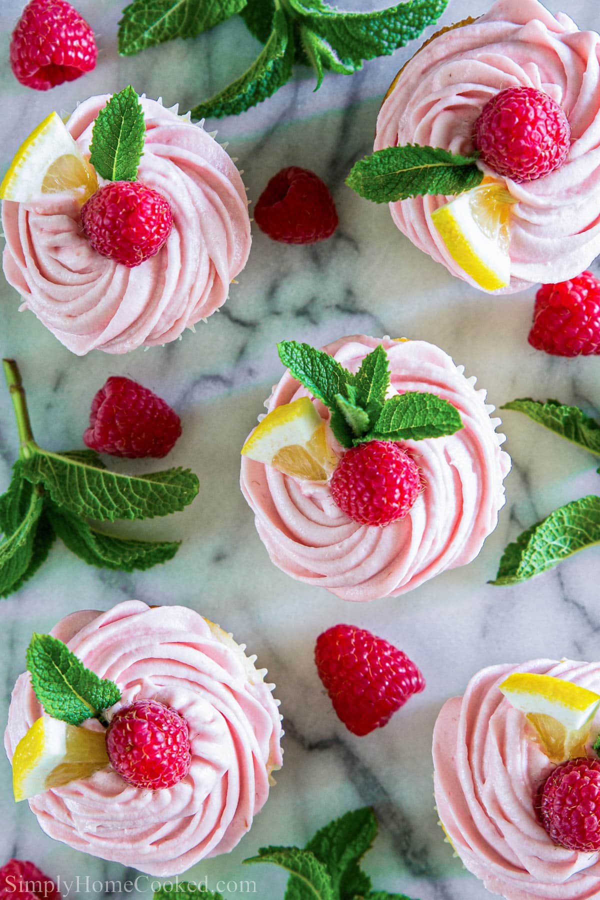 Overhead view of Lemon Raspberry Cupcakes with mint leaves, lemon slices, and raspberries.
