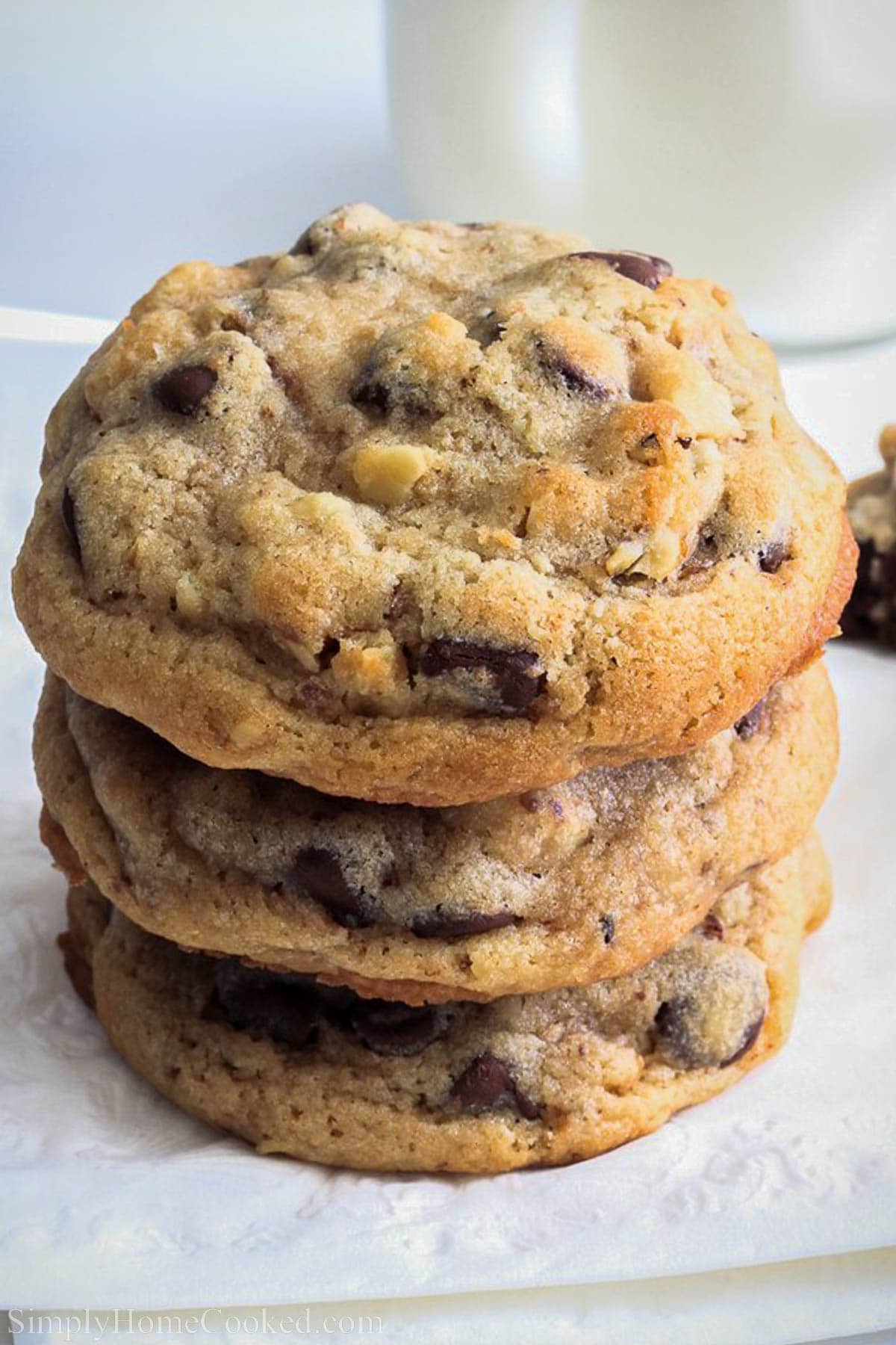 Make these Jumbo Chocolate Chip Walnut Cookies and please a crowd! Full of delicious chocolate flavor with a hint of crunch from walnuts. #chcocolatechipcookies #thecookie #metropolitancookie #walnutchocolatechipcookies #classiccookie #jumbocookies A stack of Chocolate Chip Walnut Cookies.