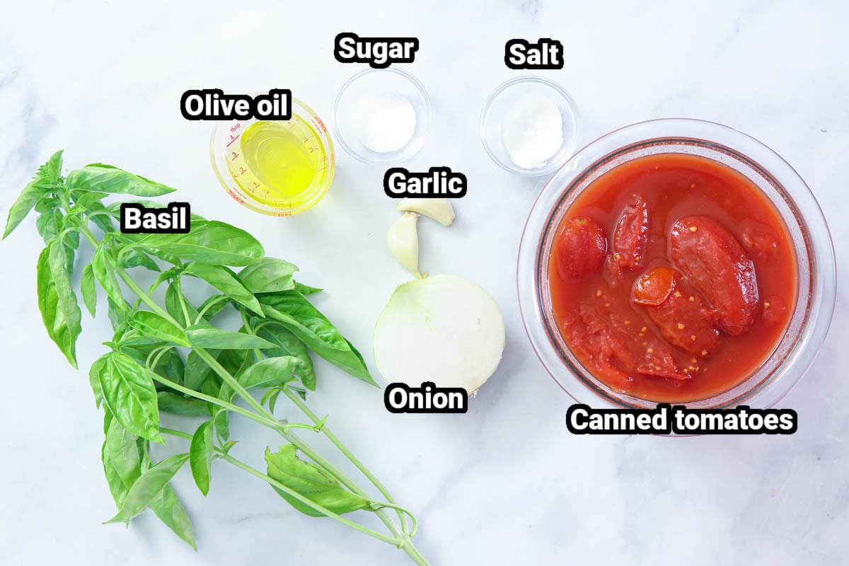 Ingredients for Pomodoro Sauce: canned tomatoes, basil, olive oil, sugar, salt, garlic, and onion.
