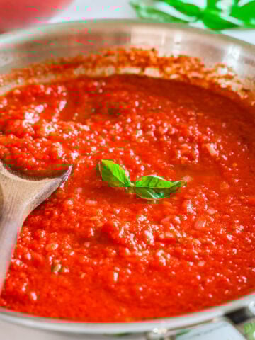 Skillet of Pomodoro Sauce stirred with a wooden spoon.