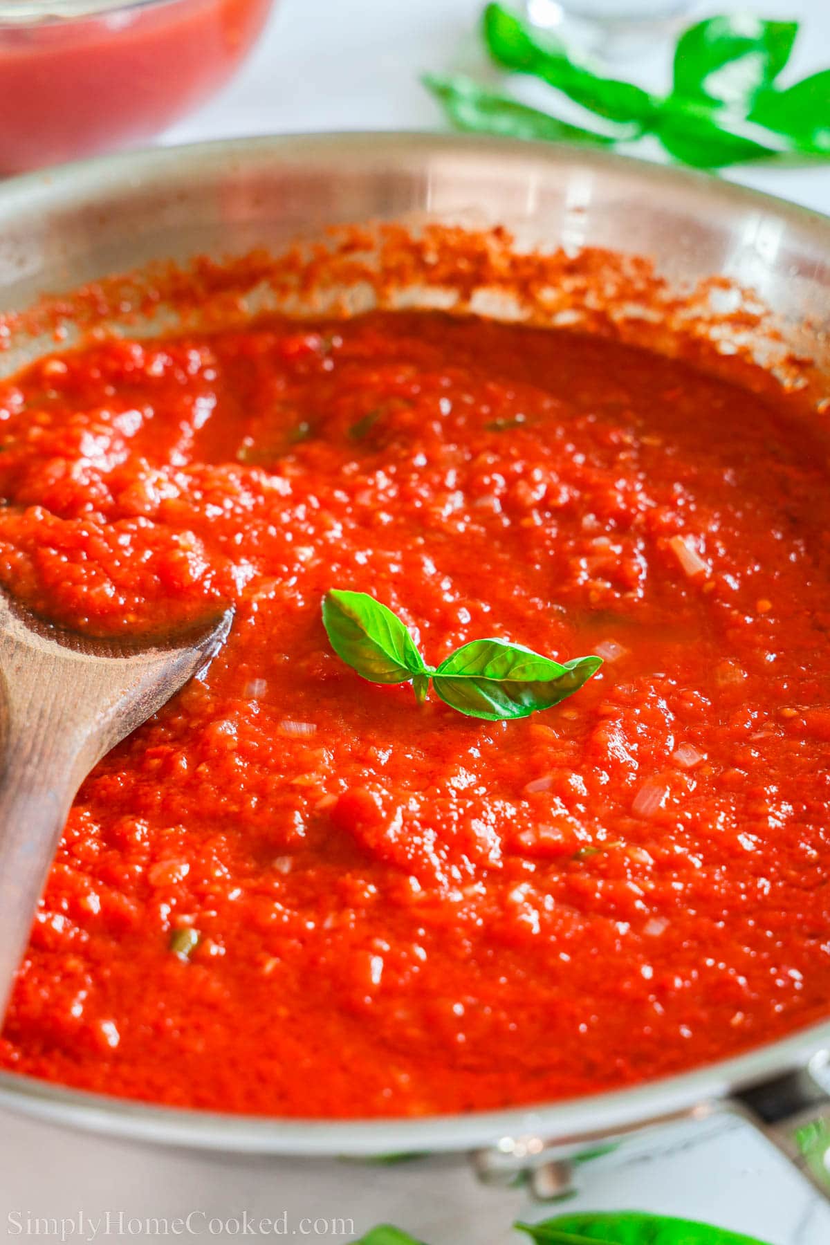 Skillet of Pomodoro Sauce stirred with a wooden spoon.