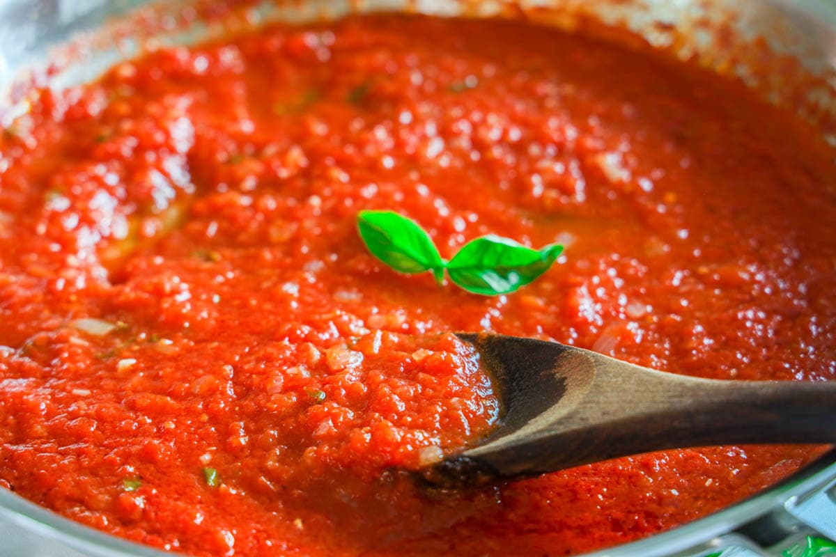 Pomodoro Sauce being stirred with a wooden spoon.