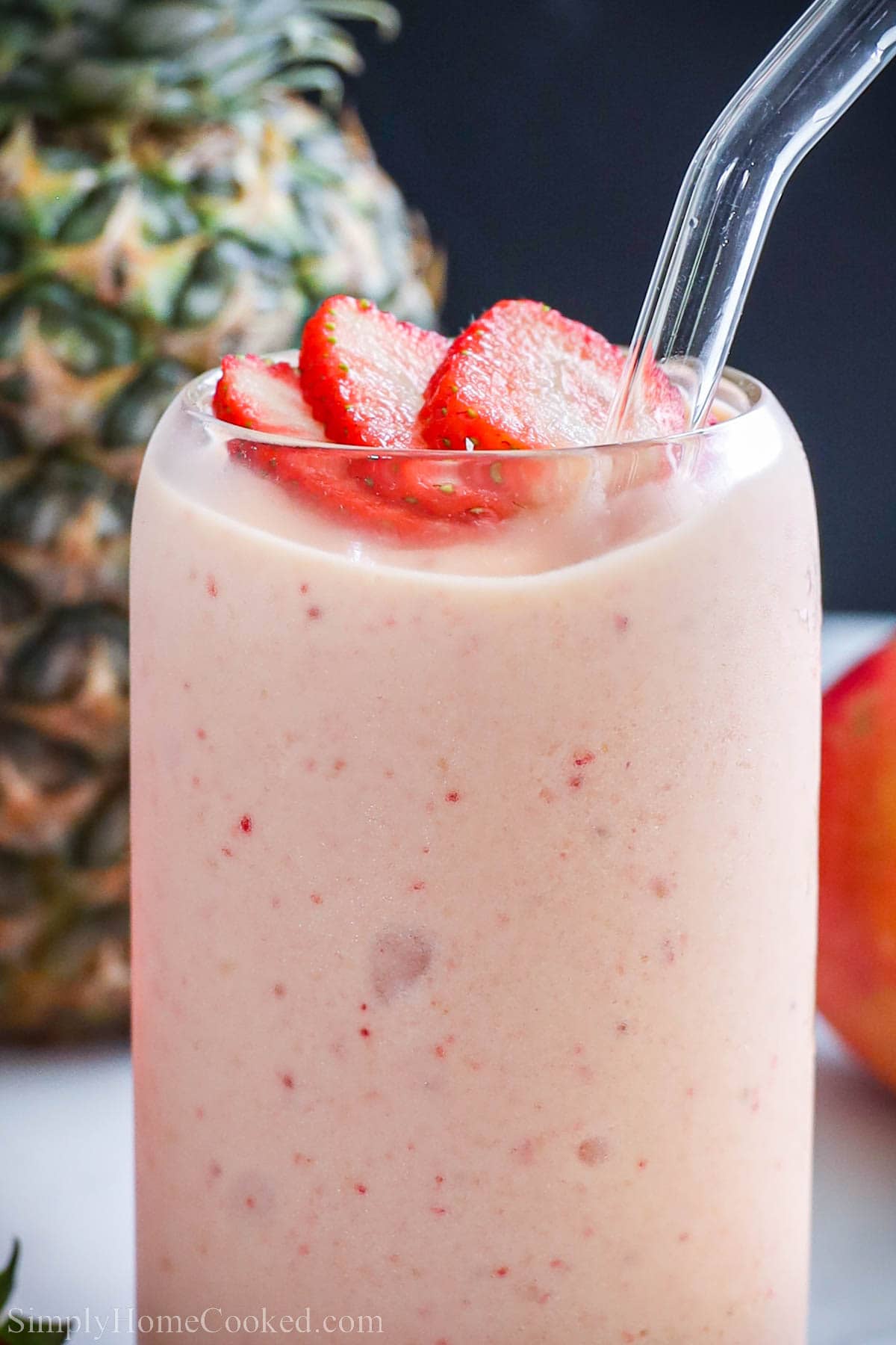 Close up of a Tropical Smoothie with sliced strawberries on top.