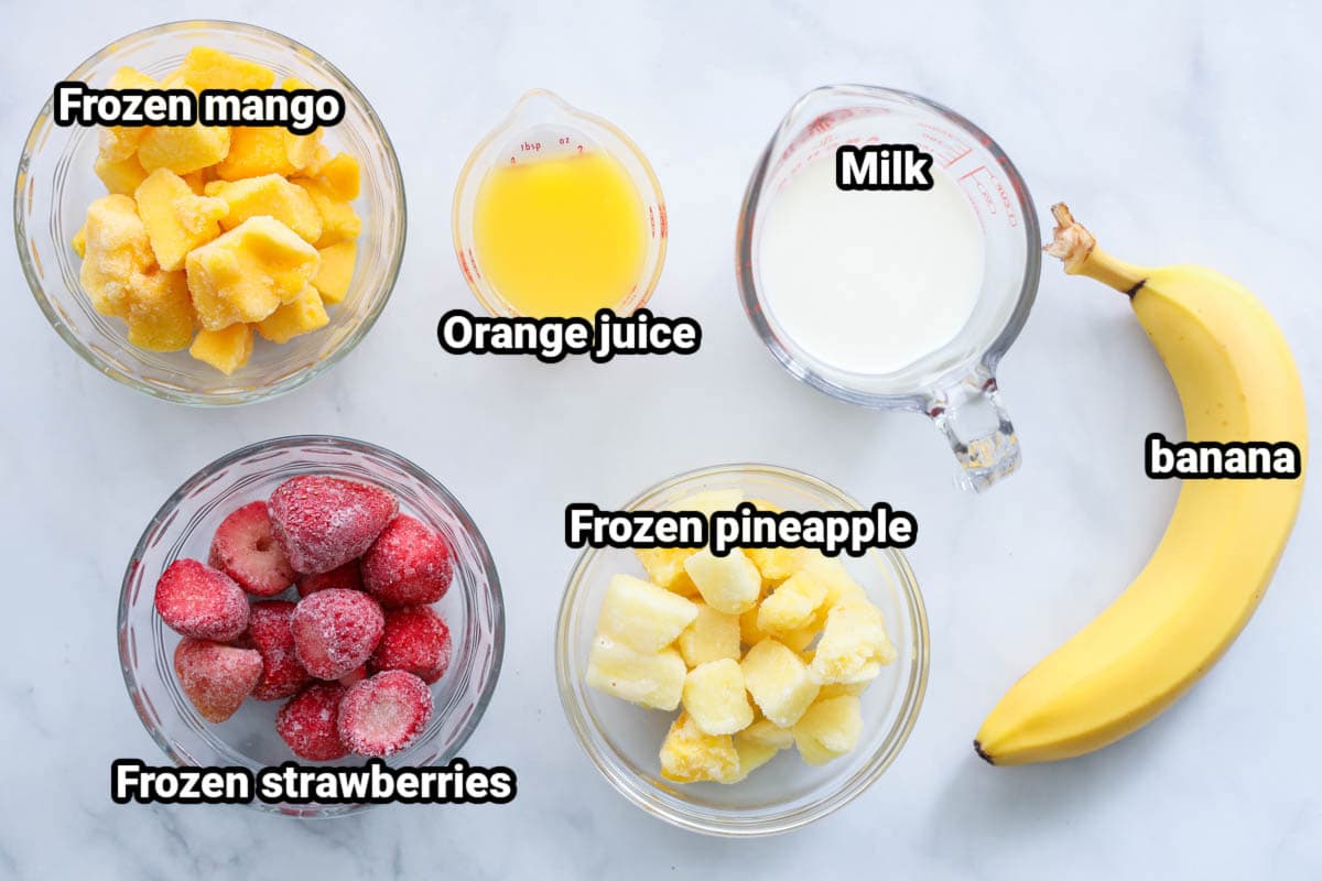 Ingredients for a Tropical Smoothie: frozen mango, frozen strawberries, orange juice, milk, banana, and frozen pineapple.