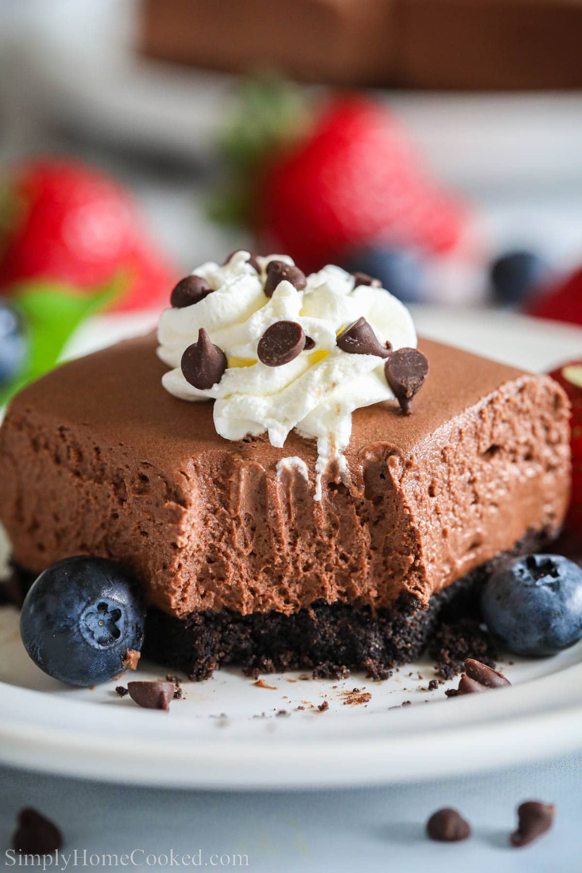 These no bake chocolate cheesecake bars are so rich, creamy, and chocolatey. Its a chocolate lovers dream dessert! #chocolatecheesecake #nobakecheesecake #cheesecakebars #cheesecake #dessertbars A No-bake Chocolate Cheesecake Bar missing a forkful and topped with whipped cream and chocolate chips.