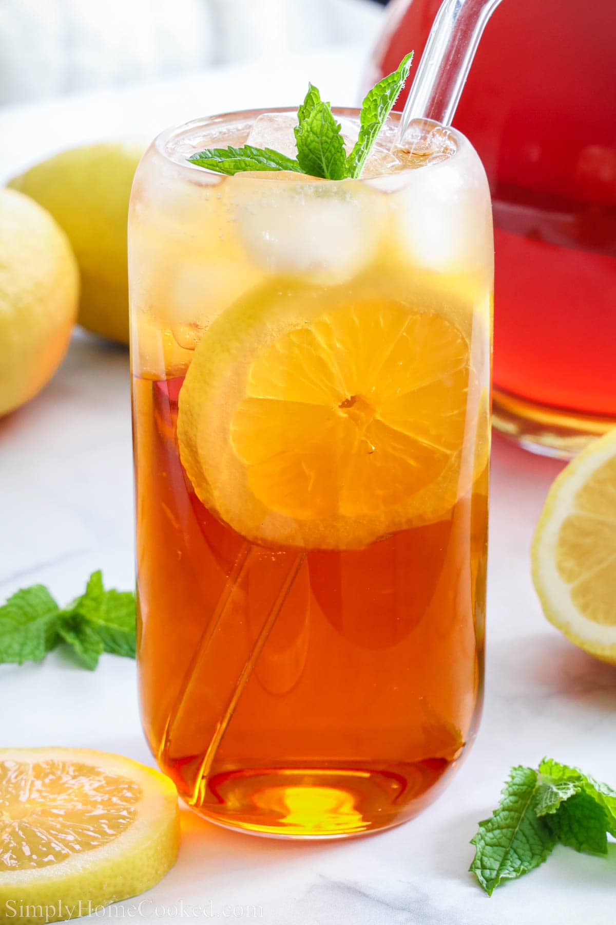 Glass of Sweet Tea with a straw and a slice of lemon, topped with mint.