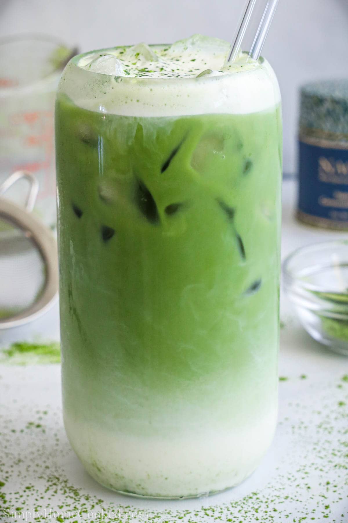 Iced Matcha Latte topped with cold foam in a glass with a straw.