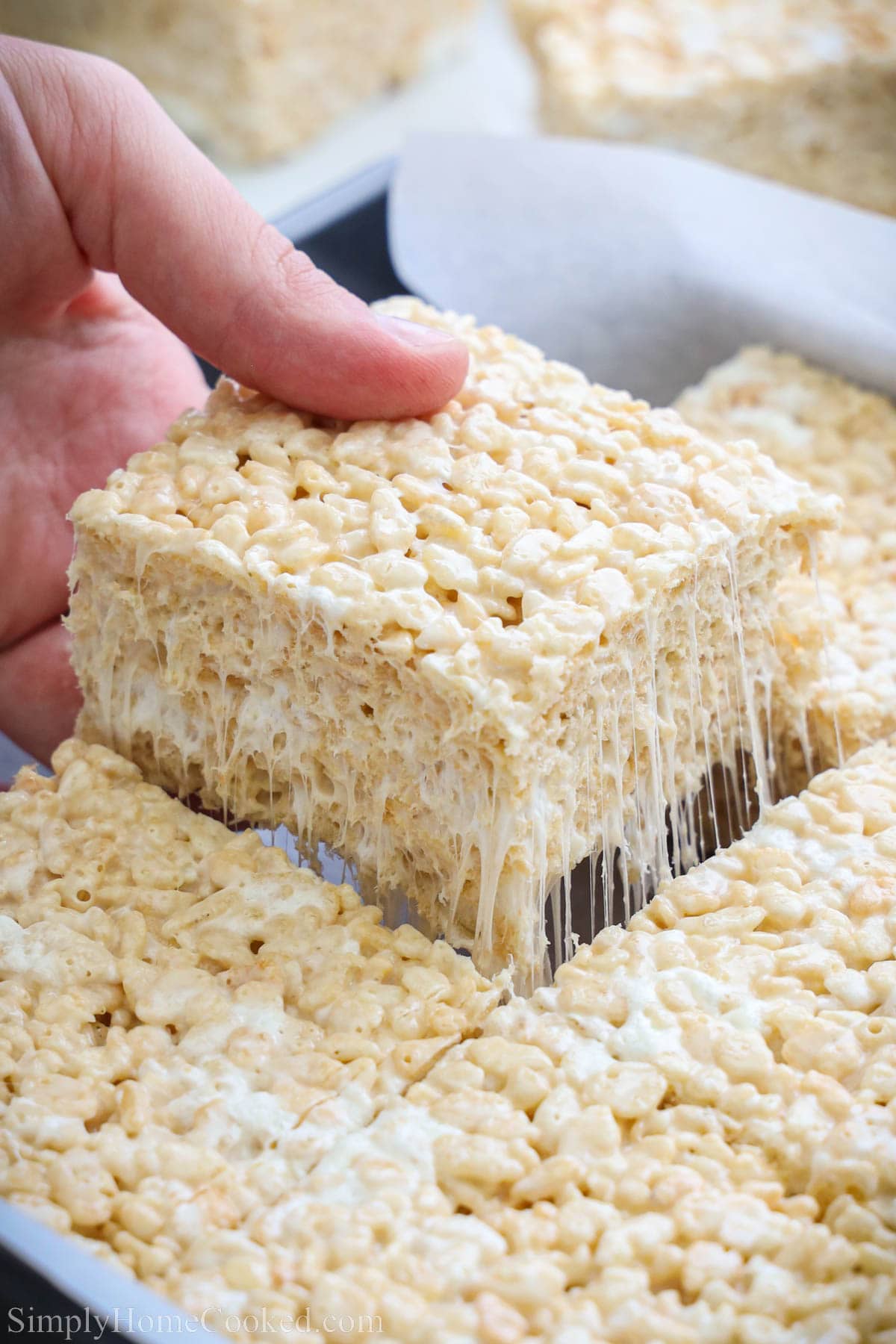 Brown Butter Rice Krispie Treats cut in a pan, one being lifted out.