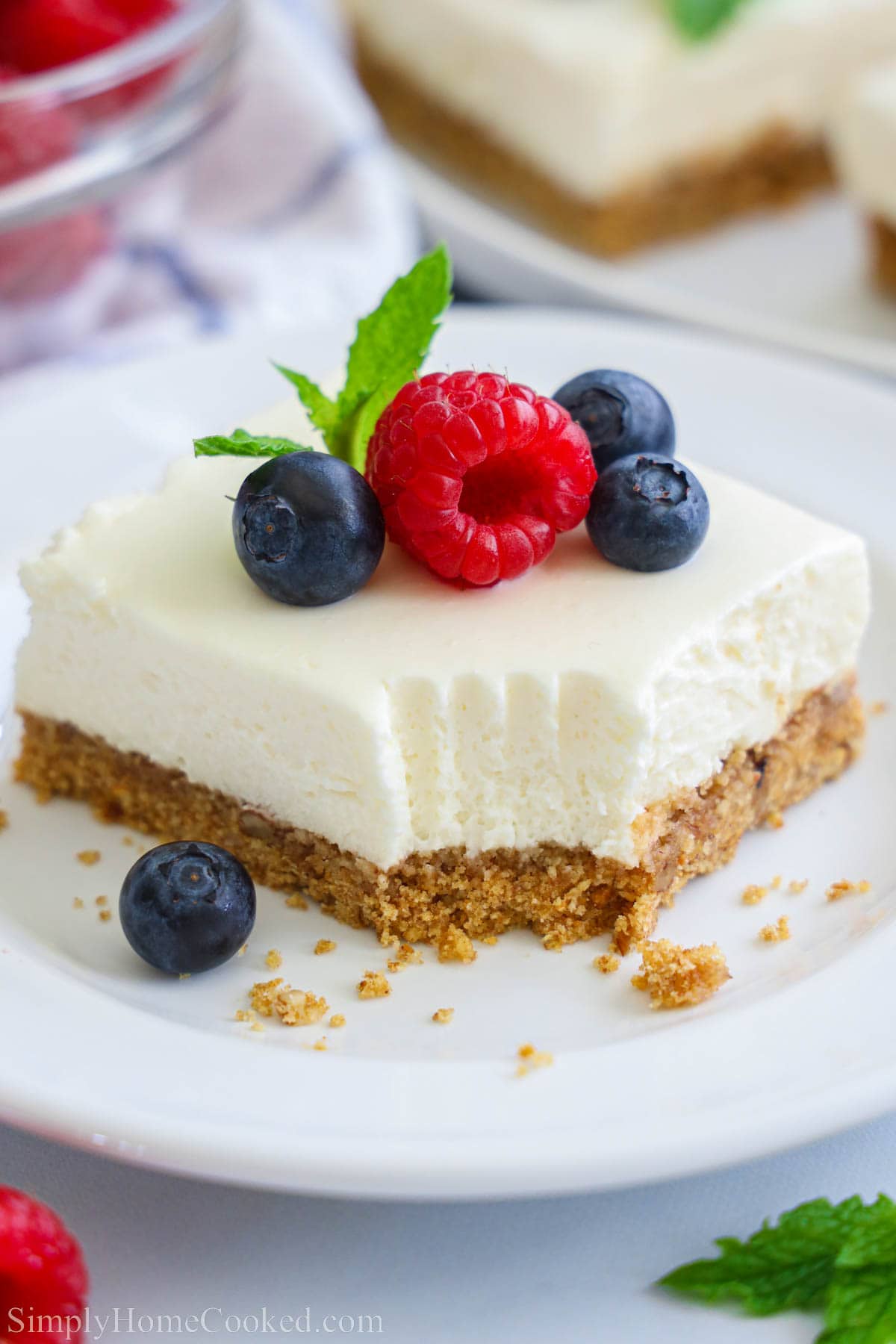 No-bake Cheesecake Bar missing a bite and topped with blueberries and a raspberry.