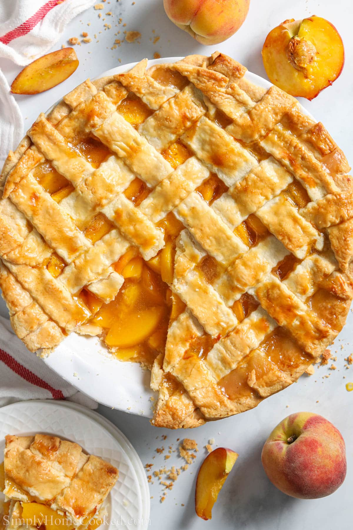 This Perfect Peach Pie has a sweet syrupy filling & flaky lattice crust. Picture perfect, its delicious flavor will make it everyone's favorite.summer treat. #homemadepeachpie #homemadepeachpierecipe #bestpeachpie #besthomemadepeachpie Perfect Peach Pie missing a piece surrounded by fresh peaches.
