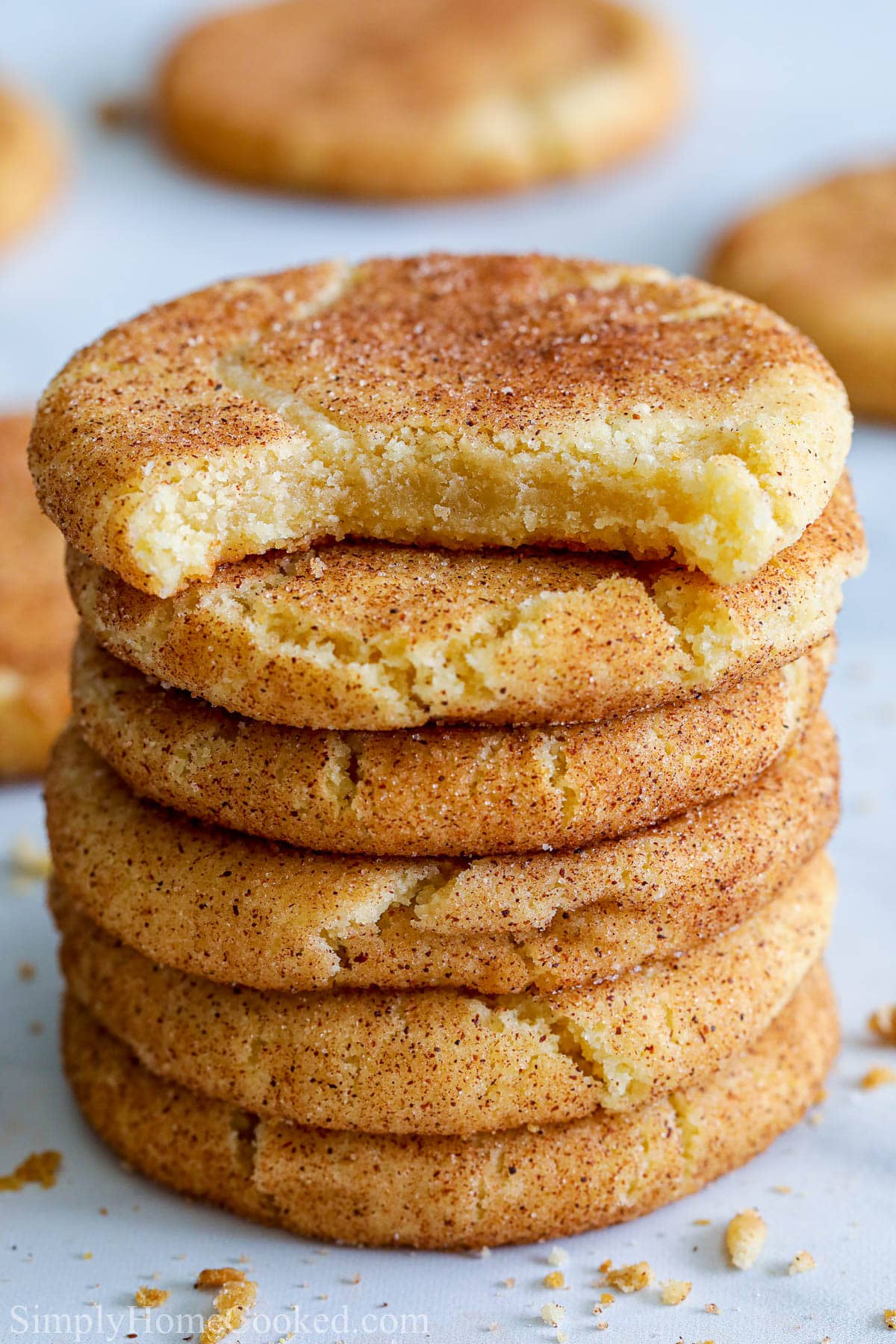 These Soft Snickerdoodle Cookies are so delicious & chewy. Their distinct flavor & cinnamon-sugar coating are perfect for any holiday platter. #snickerdoodles #snickerdoodlecookies #softsnickerdoodles #softsnickerdoodlecookies Stack of Snickerdoodle Cookies, the top one missing a bite.