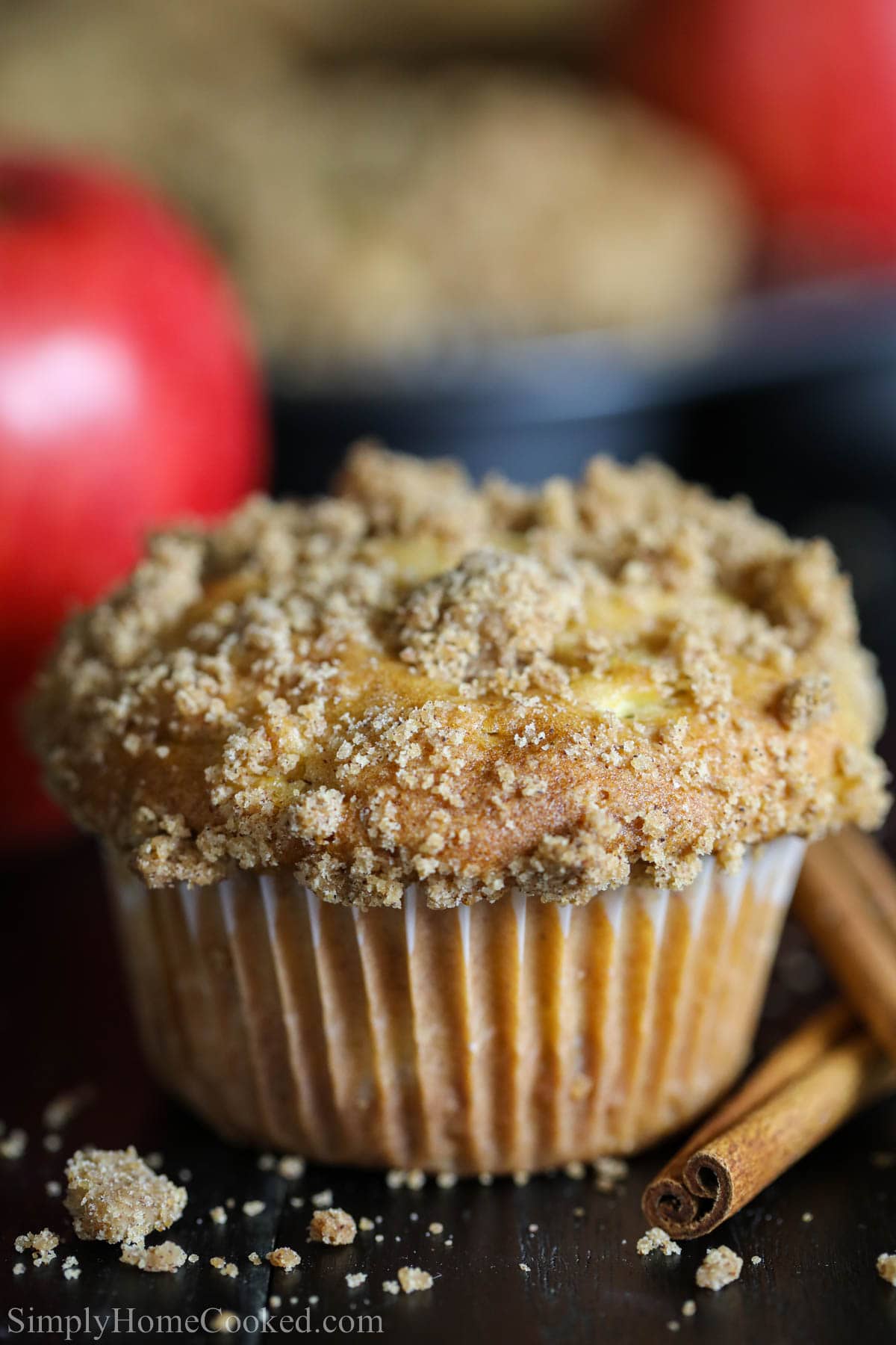 Delicious and moist Cinnamon Apple Muffins. A perfect dessert to make your day, and a perfect recipe that has apple bits and cinnamon spice! #applemuffins #muffinrecipe #bestmuffins #easymuffins #appledessert #apples #falldessert Close up of a Cinnamon Apple Muffin with cinnamon sticks nearby.