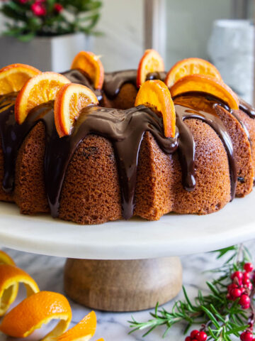 Cranberry Orange Bundt Cake topped with chocolate ganache and orange slices.