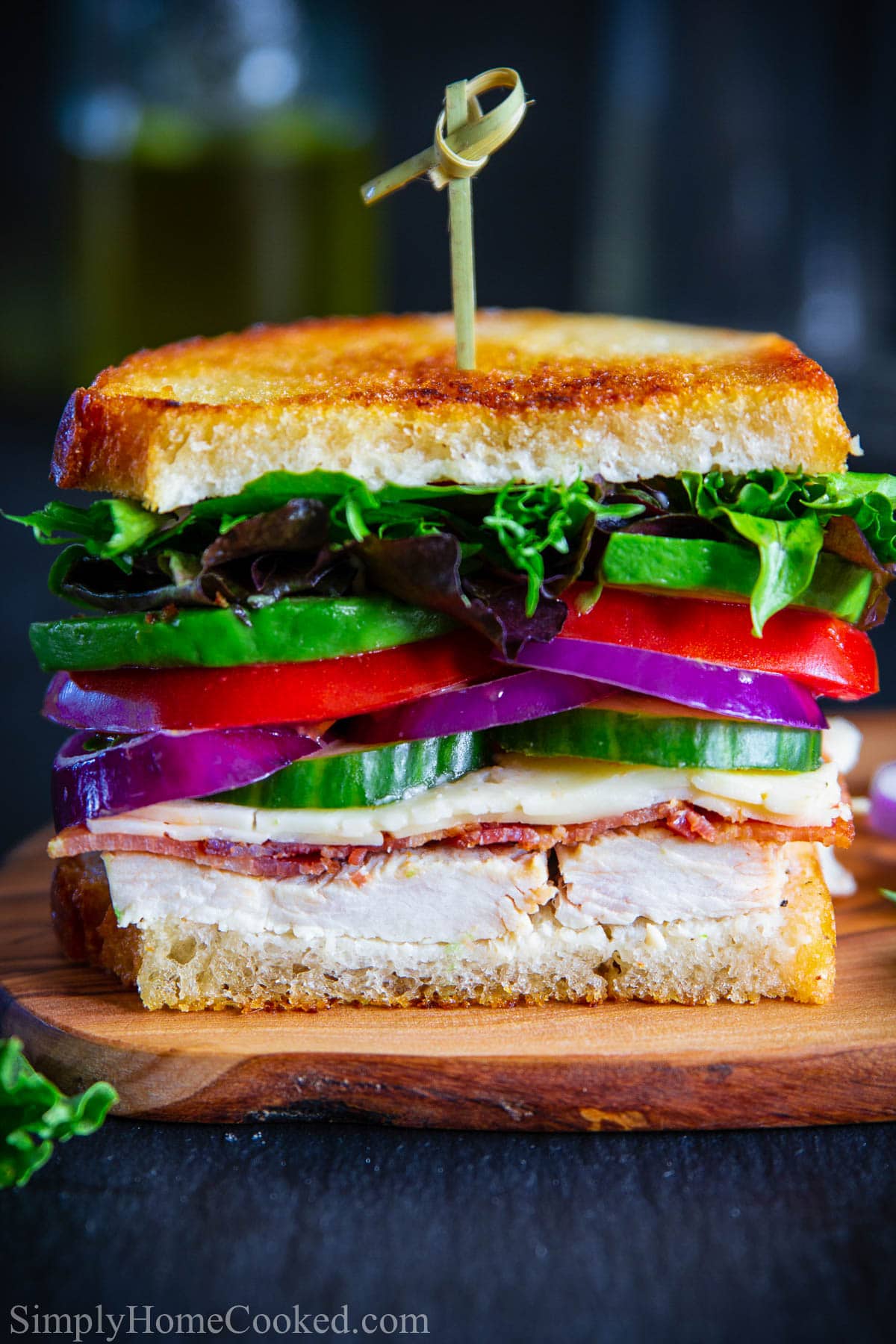 This leftover Turkey Sandwich is the ultimate way of enjoying every bit of those tasty Thanksgiving leftovers. This grilled sandwich is loaded with turkey, bacon, Havarti cheese, red onion, avocado, and tomatoes. #sandwich #turkeysandwich #leftoversandwich #turkeyleftoversandwich #thanksgivingsandwich Half a Turkey Melt with a toothpick through it.