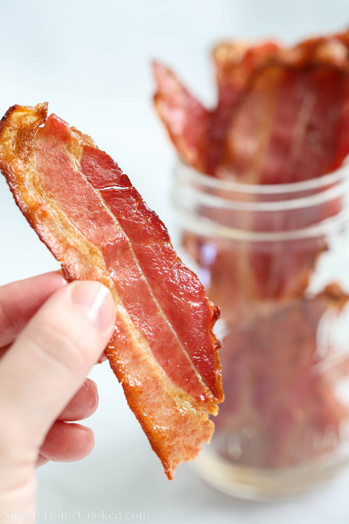Hand holding crispy Air Fryer Bacon.