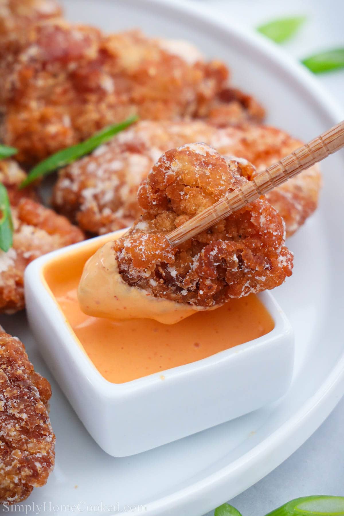 Piece of Chicken Kaarage being dipped into sauce with chopsticks.