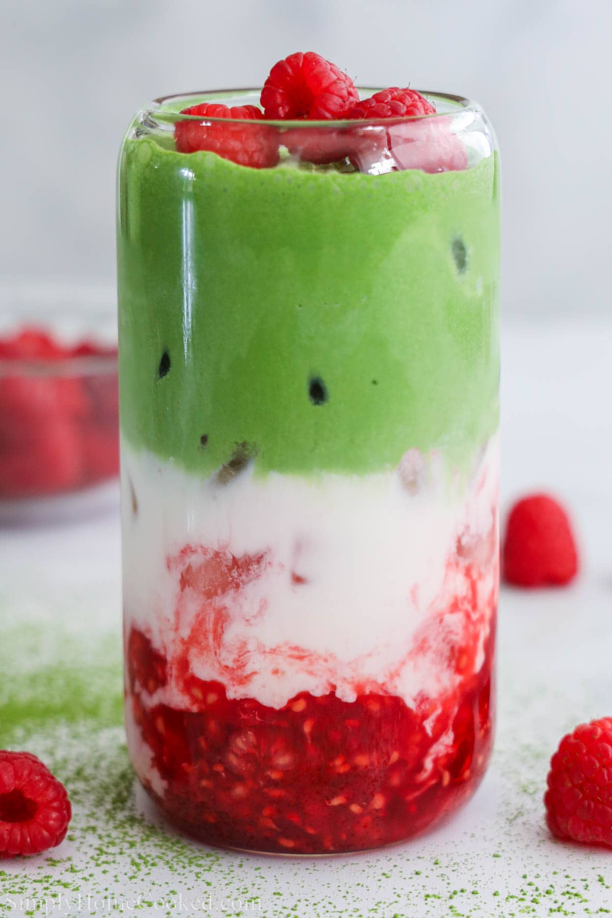 Raspberry Matcha Latte layers with raspberries, white chocolate milk, and matcha cold foam.