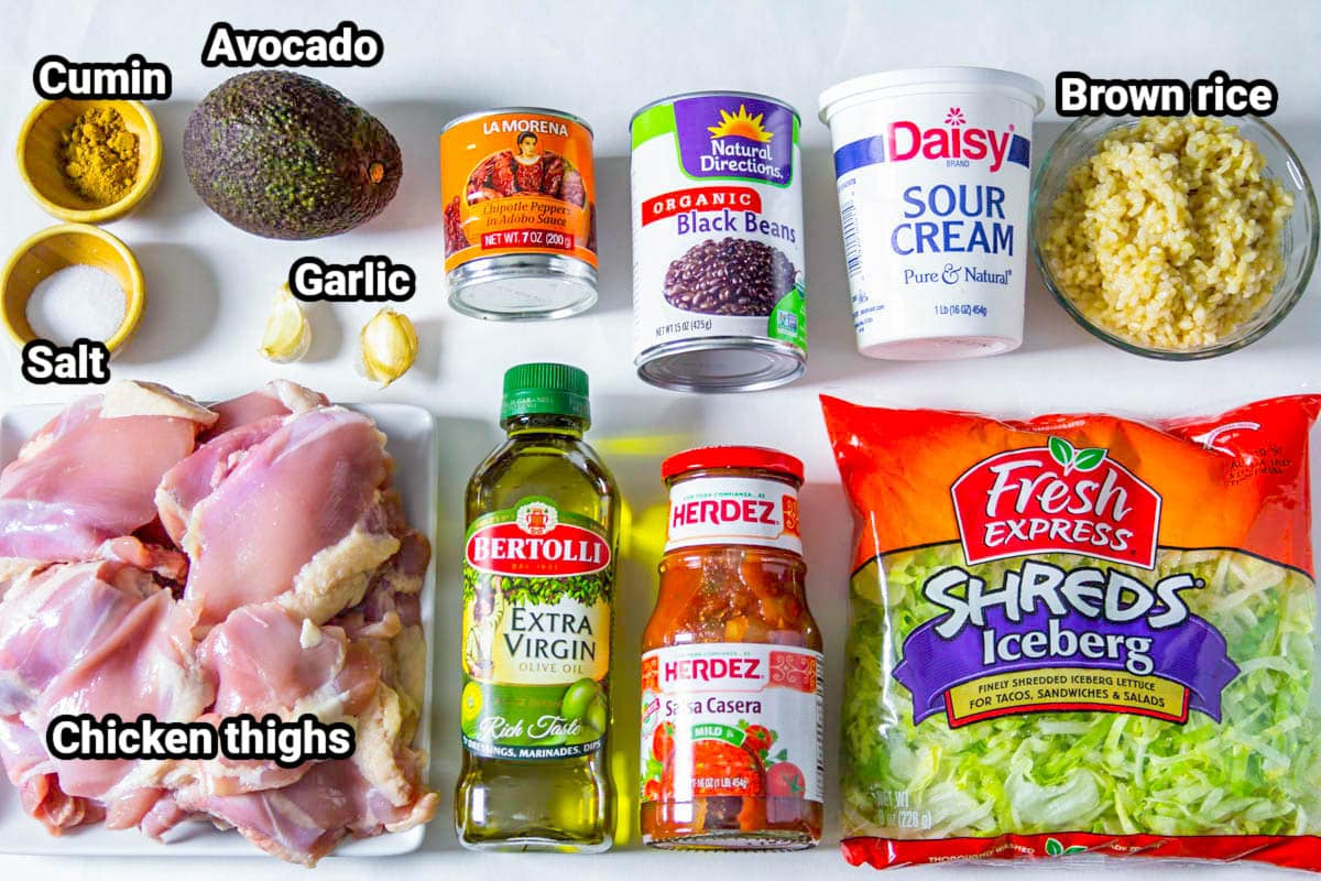 Ingredients for Chipotle Chicken Bowl: cumin, salt, avocado, garlic, adobo peppers, black beans, sour cream, brown rice, lettuce, salsa, olive oil, and chicken thighs.