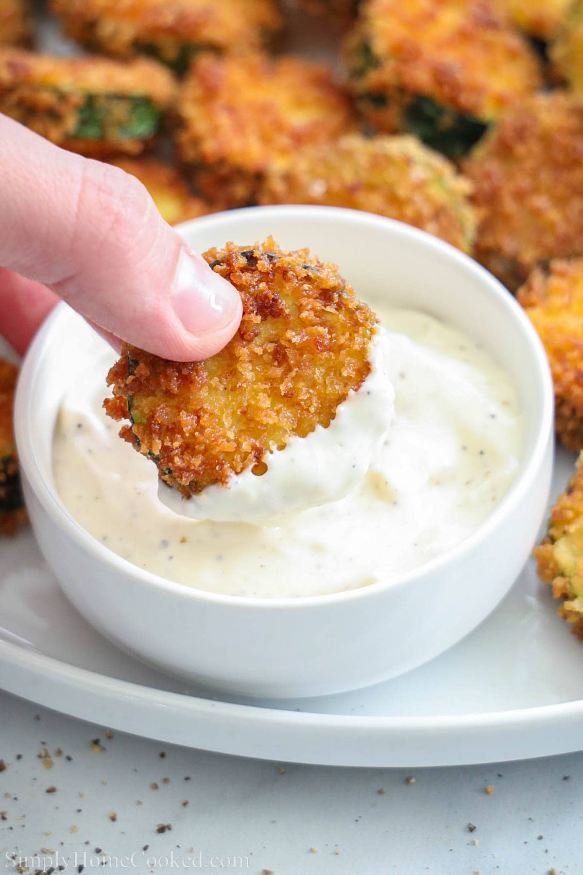 Fried Zucchini being dipped into garlic aioli sauce. 