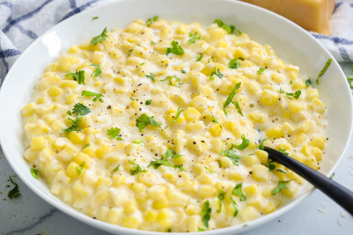 Creamed Corn in a bowl with a spoon.