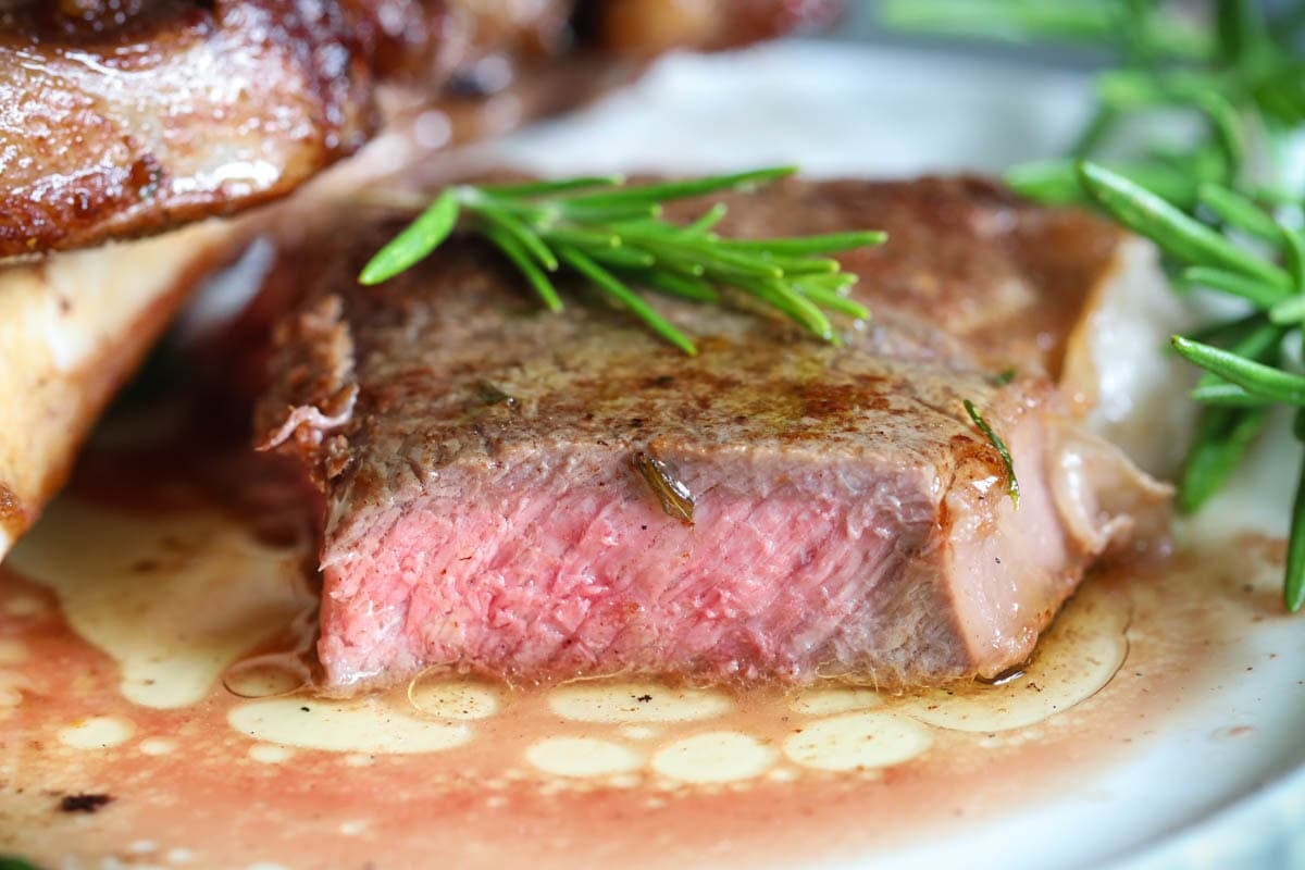 Cut of ribeye steak topped with rosemary. 