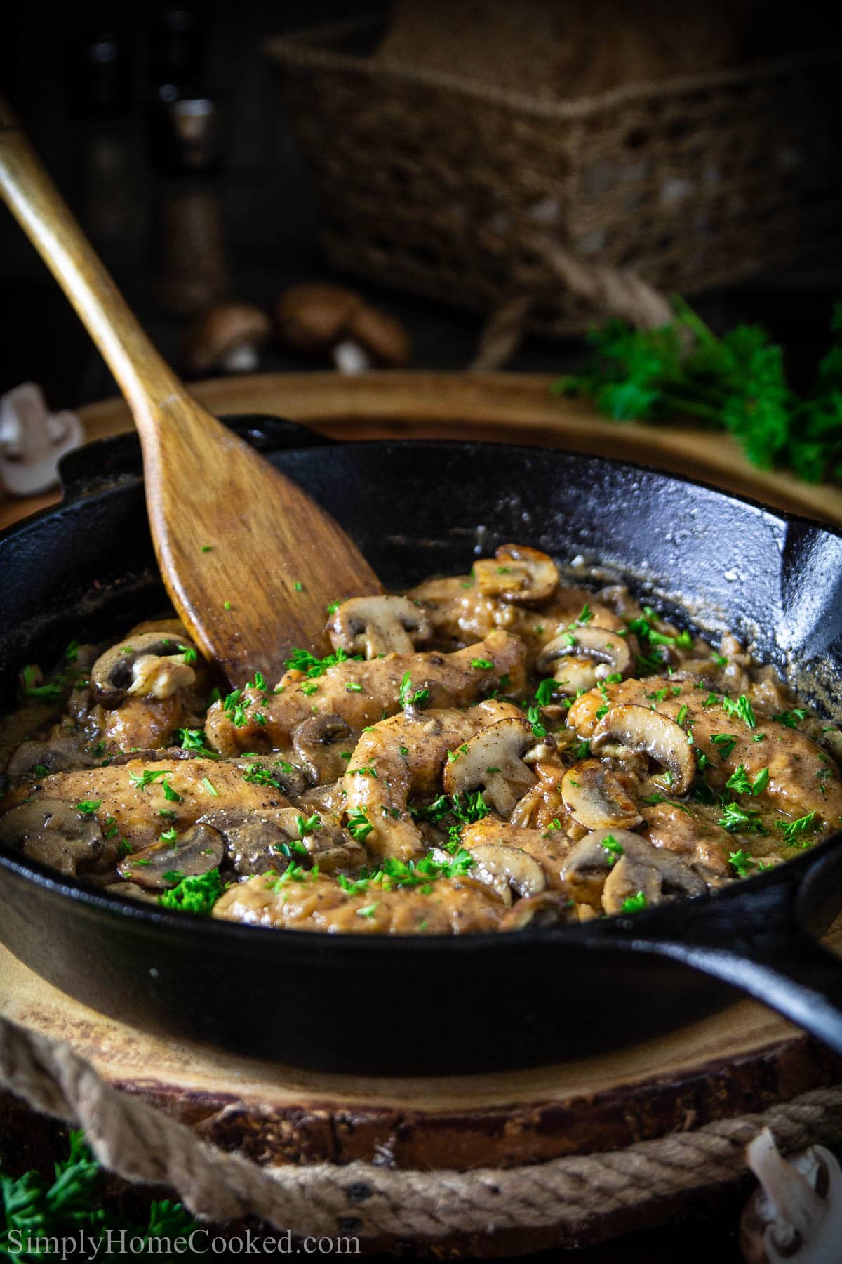 Pan of Chicken Marsala being stirred with a wooden spatula.