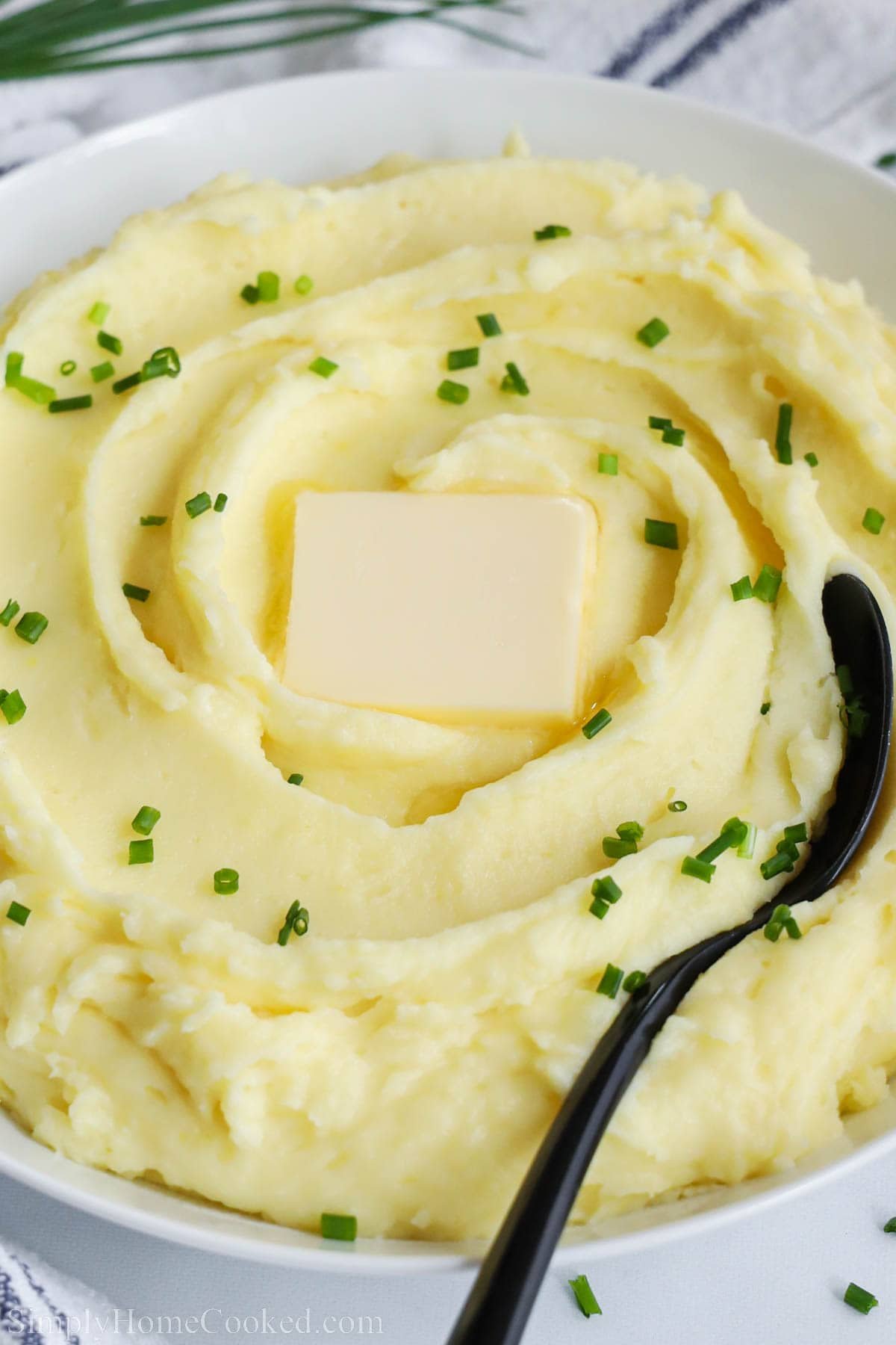 Close up of a bowl of Yukon Gold Mashed Potatoes with butter and a spoon. 