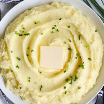 An overview of Yukon Gold Mashed Potatoes in a bowl topped with a pat of butter.