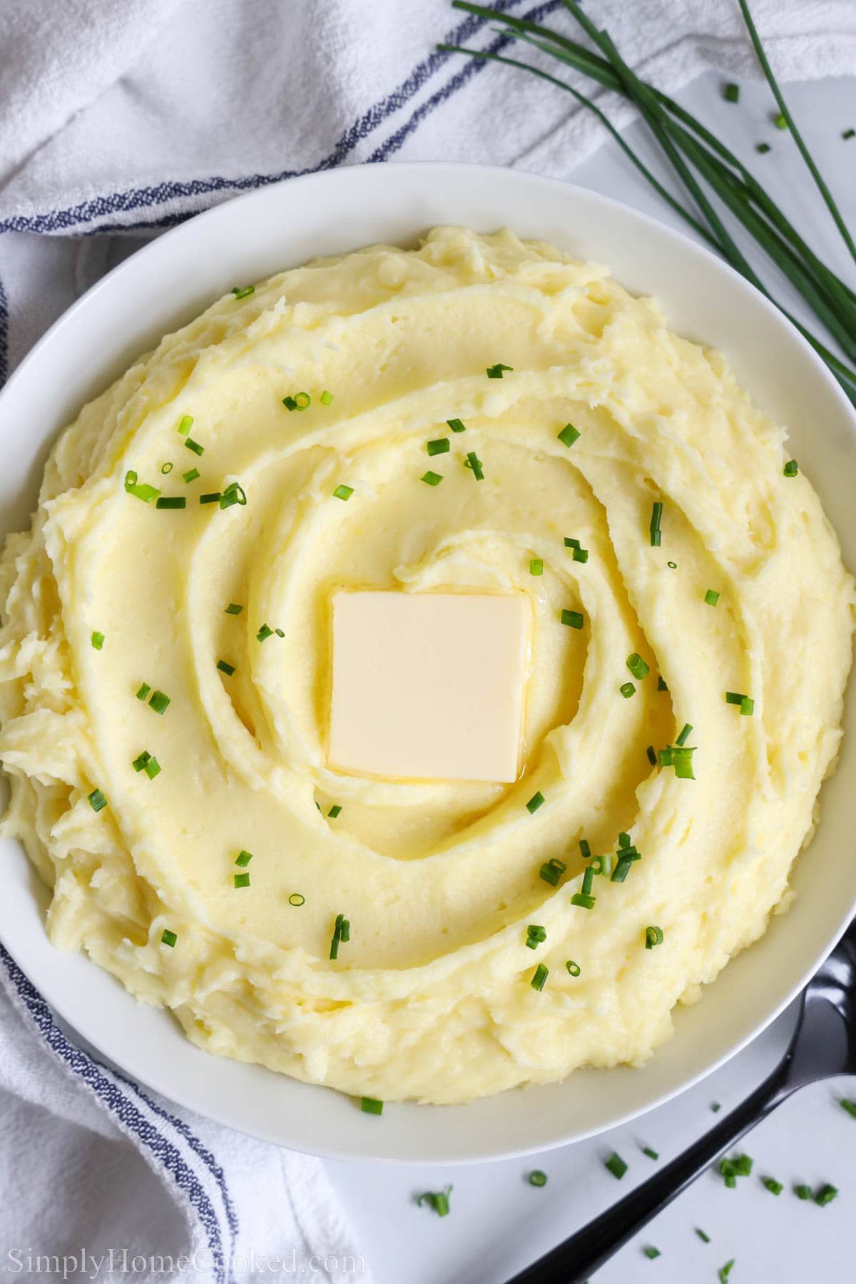 An overview of Yukon Gold Mashed Potatoes in a bowl topped with a pat of butter.