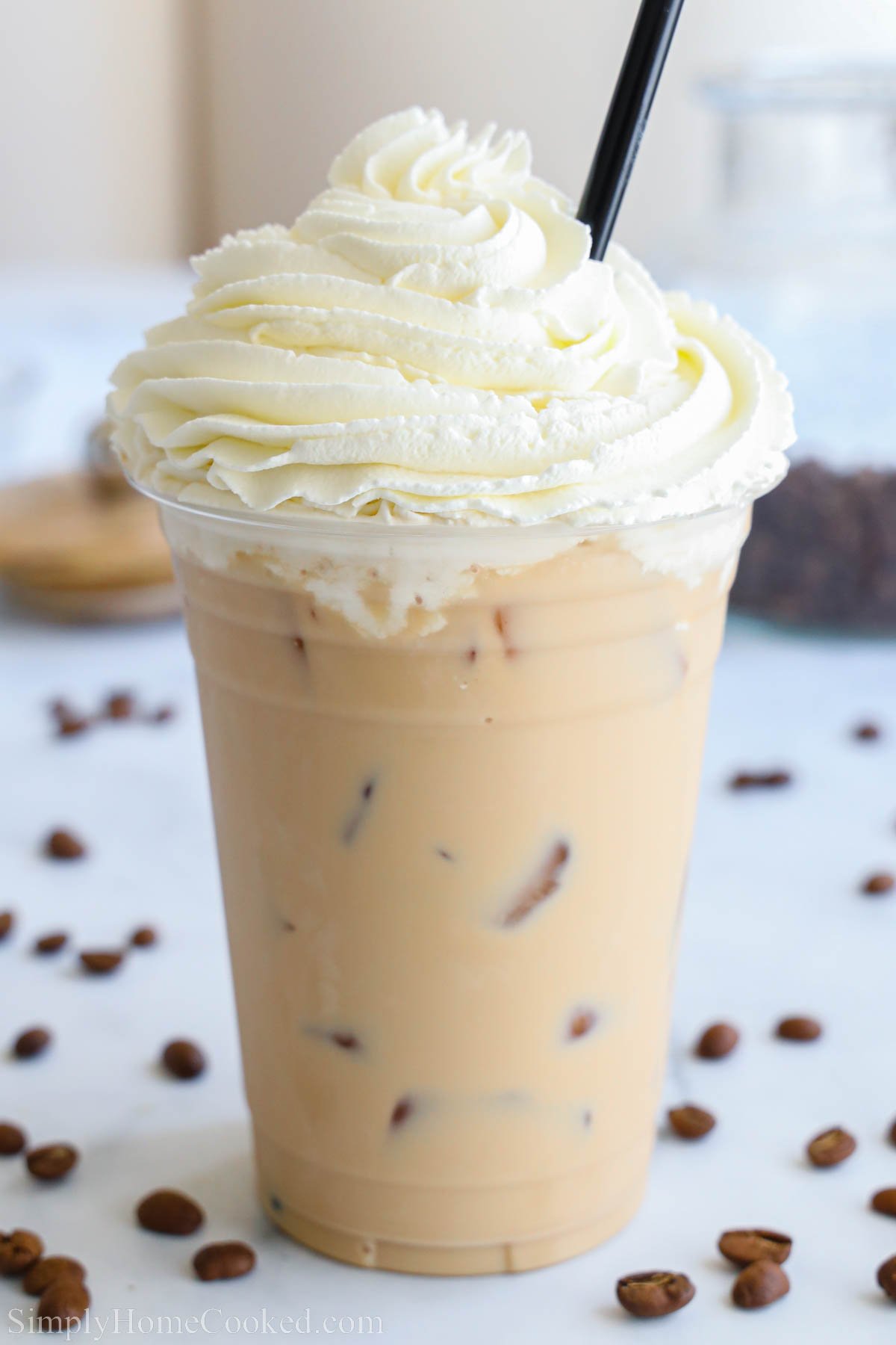 Iced White Chocolate Mocha topped with whipped cream, with a straw.