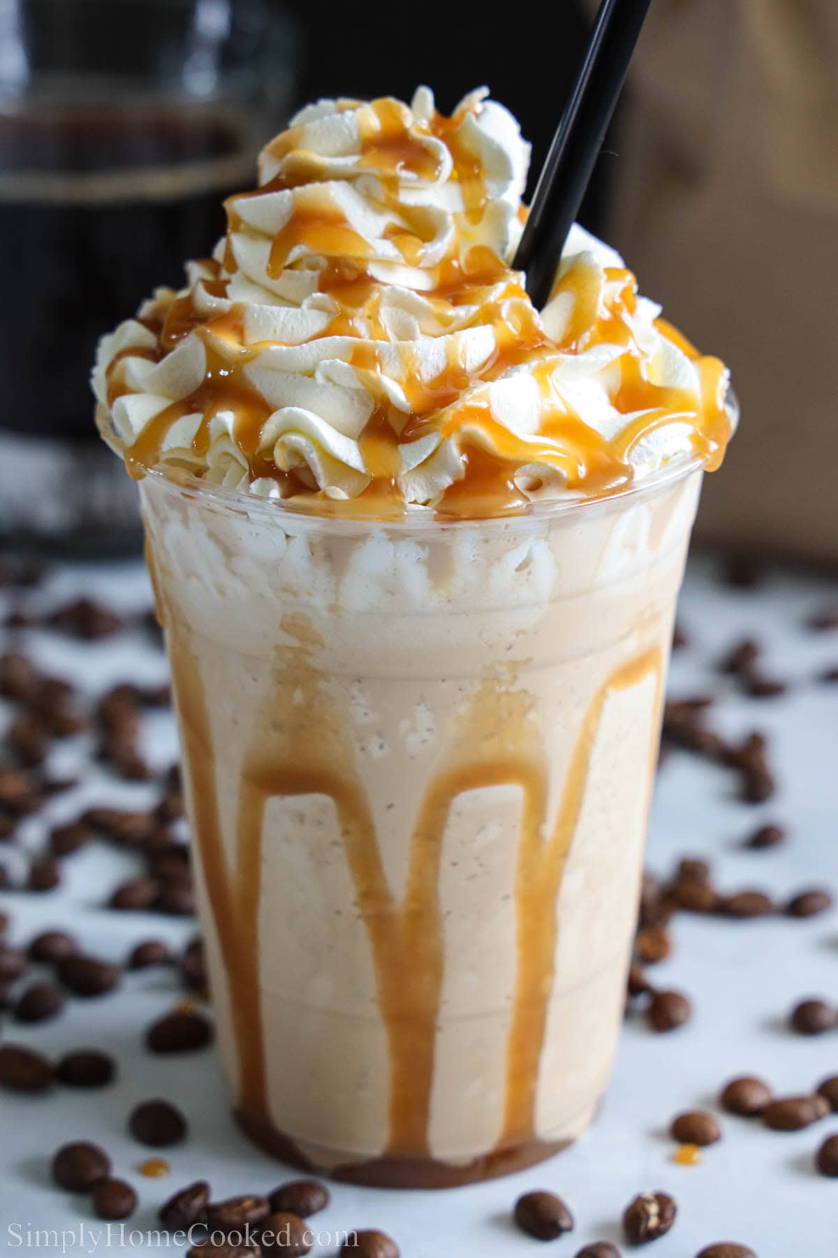 Caramel Frappuccino with a straw and topped with caramel sauce and whipped cream.