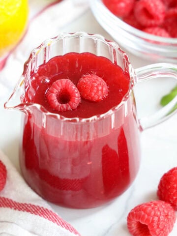 Raspberry Coulis in a pitcher with raspberries.