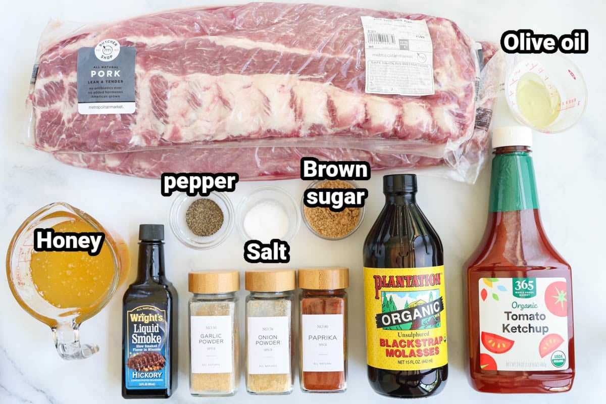 Ingredients for Oven Baked Ribs: spare ribs, olive oil, honey, ketchup, molasses, brown sugar, liquid smoke, garlic powder, onion powder, paprika, salt, and pepper.