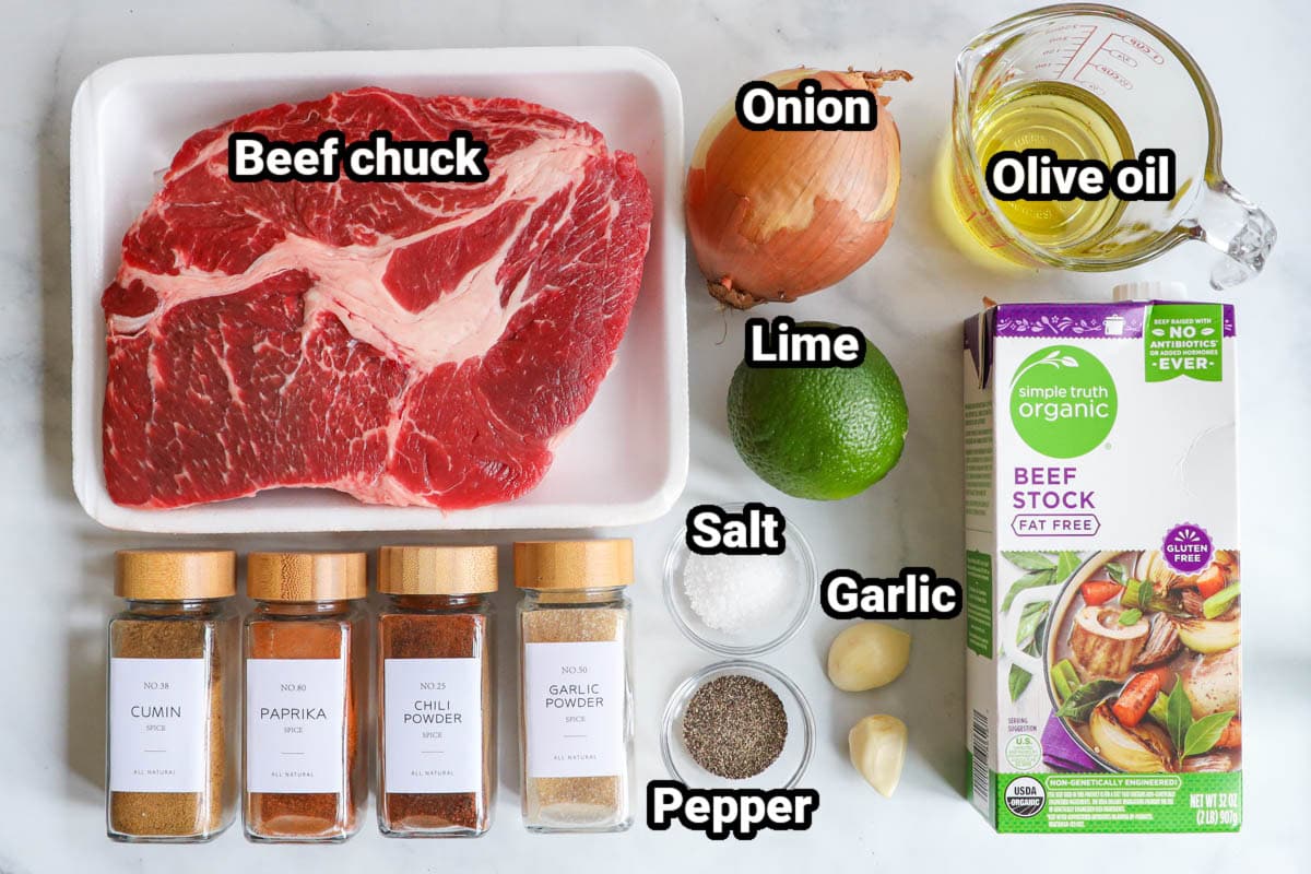 Ingredients for Shredded Beef Tacos: beef chuck, onion, lime, olive oil, beef stock, garlic, salt, pepper, garlic powder, paprika, chili powder, and cumin.
