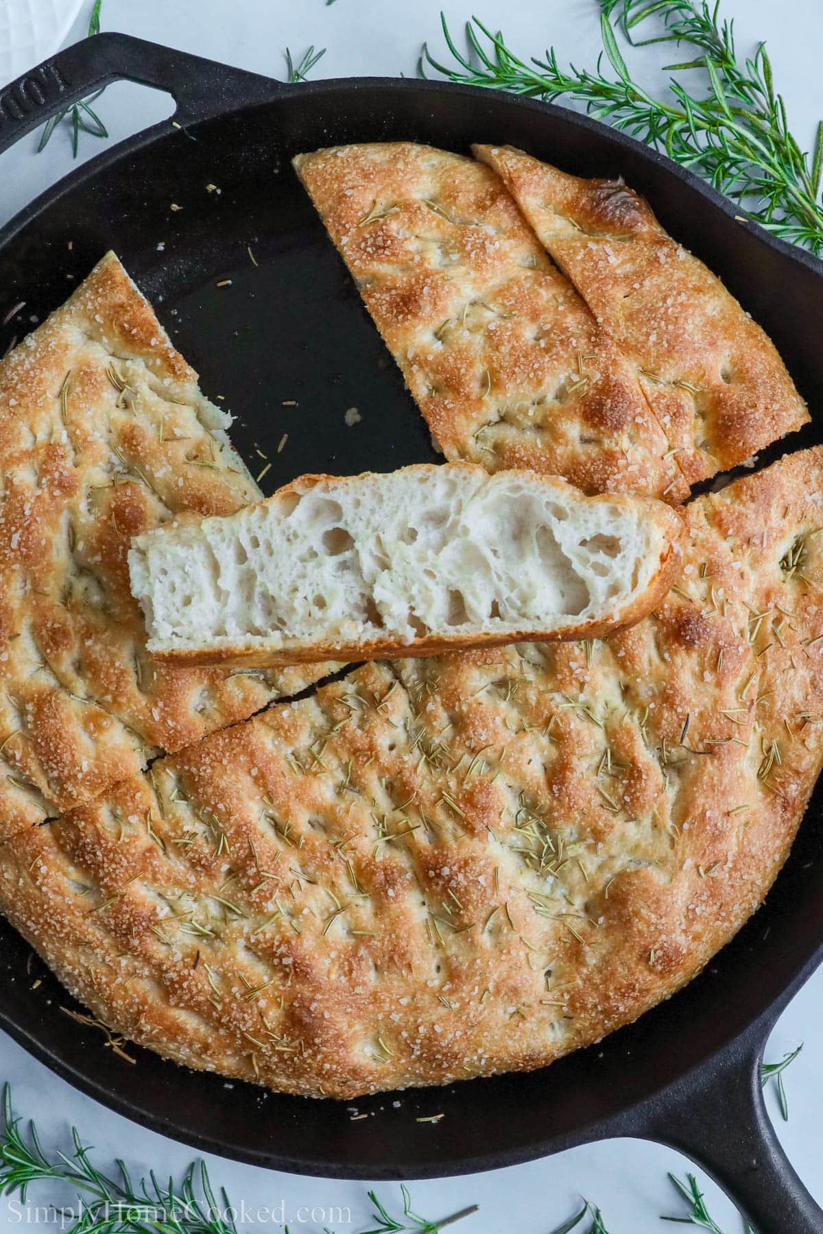 Sourdough Focaccia in a cast iron pan, cut, with one slice on top/