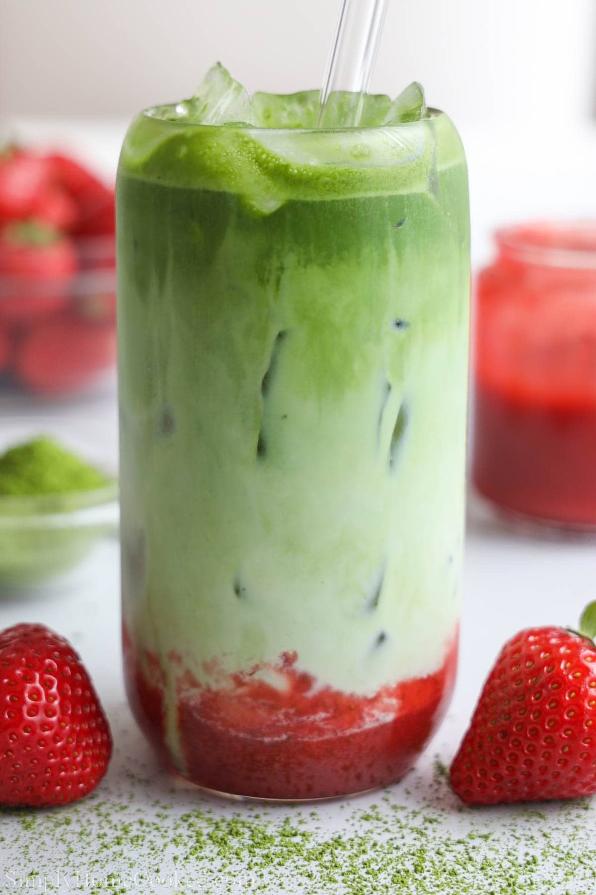 Close up of a Strawberry Matcha drink layered with matcha, milk, and strawberry puree, with a straw.