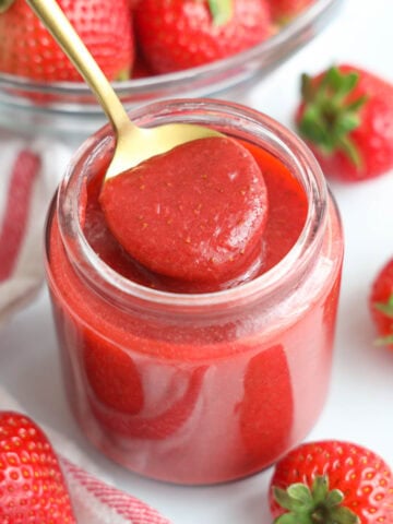 Close up of Strawberry Puree in a jar with a spoon.