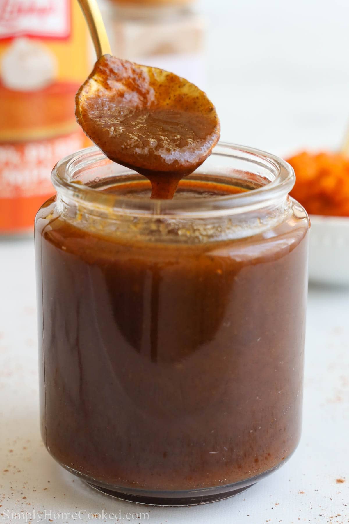 A spoon drizzled Pumpkin Spice Syrup into a jar.